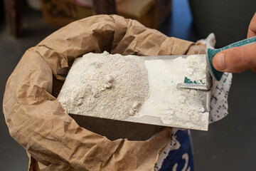 Male hand holding putty cement on a trowel from a paper bag sack, home renovation concept