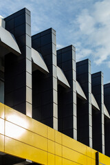 Gray metal columns and yellow border, minimalist detail of a building exterior against blue sky