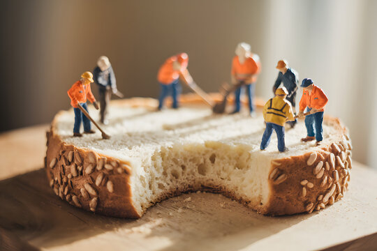 A whimsical and humorous image of miniature construction workers diligently working on a slice of bread. AI Generated - Powered by Adobe