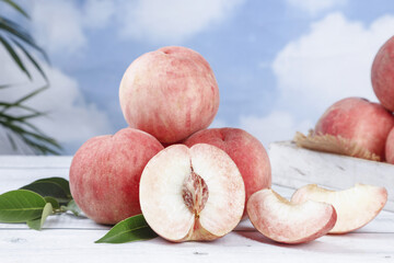 Fresh Red Peaches Whole and Sliced on White Marble Surface with Green Leaves