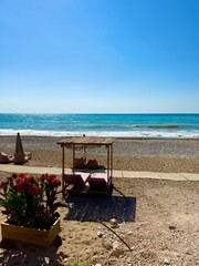 Public beach, summer, beautiful sunny weather. Picturesque beach, waves crashing on the sandy shore. Sea waves beat against the rocks. Cyprus Island, umbrellas, tourist boats, Mediterranean Sea.