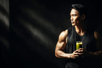After an intense workout, a man enjoys a refreshing glass of matcha in a dimly lit gym, focusing on hydration and recovery while savoring the moment of calm