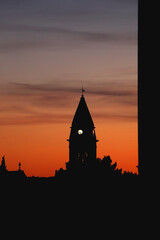 Naklejka premium Silhouette of a historic bell tower and sunset sky.
