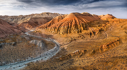 Breathtaking aerial view of colorful mountains and canyons illuminating under dramatic sky in...
