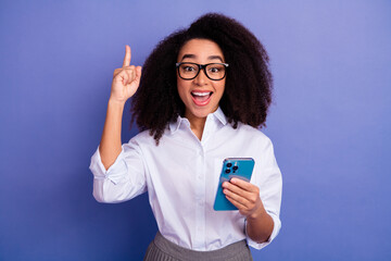 Happy young professional holding smartphone making a gesture while standing on a violet background