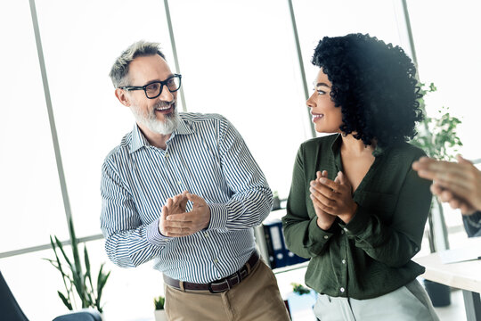 Professional coworkers sharing a joyful moment in a modern office environment while celebrating teamwork and success together - Powered by Adobe