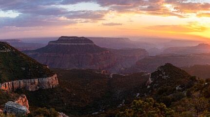 This scenic sunset panorama of Grand Canyon National Park features a colorful sky over illuminated canyon walls.