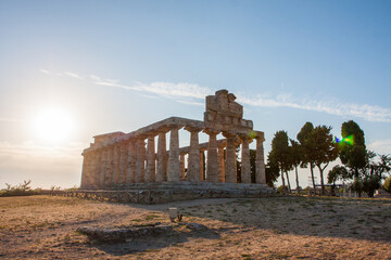 View of the ancient Greek temple ruins standing majestically against the bright sun, a symbol of history and architectural prowess, Paestum, Campania, Italy.
