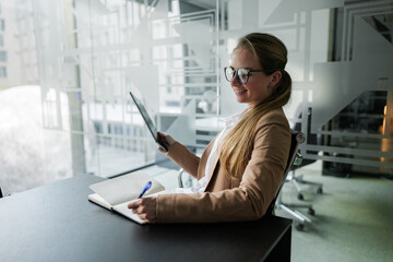 Business professional engaged in work at a modern office, taking notes and reviewing information on...
