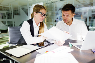 Obraz premium Collaboration in a modern office as two professionals discuss ideas while reviewing documents and sharing insights with technology on the table
