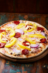 Pizza with chorizo ​​sausage, mozzarella cheese and yellow pepper. Rustic wooden background. Soft focus.	