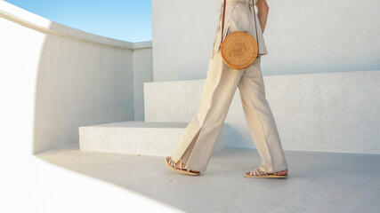 Woman walking on stairs in summer outfit with woven bag