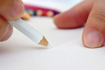 An artist or hand is using colored pencils to draw or paint according to their imagination. Using colored pencils to draw, paint, paint.