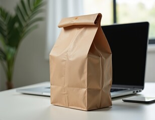 Takeaway and Delivery. A simple brown paper bag sits on a desk next to a laptop and smartphone, suggesting a casual work environment.