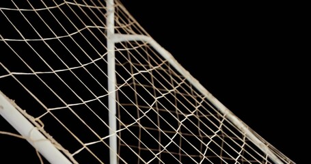 Displaying soccer goal corner with metal posts supporting diamond netting against black background