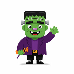 Obraz premium A cheerful Frankenstein's monster child waves hello while holding a Halloween candy, against a white background.