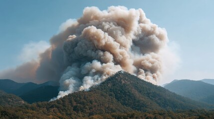 Dramatic Smoke Plume Erupting from Mountainous Landscape Under Clear Blue Sky During Wildfire Conditions in Nature's Untamed Beauty