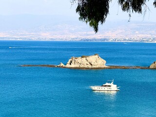 Public beach, summer, beautiful sunny weather. Picturesque beach, waves crashing on the sandy shore. Sea waves beat against the rocks. Cyprus Island, umbrellas, tourist boats, Mediterranean Sea.