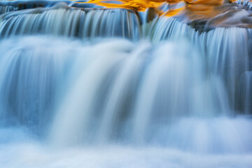 Abstract landscape of a cascade at Bond Falls captured with motion blur and illuminated by reflected color from sunlit autumn maples,  Ottawa National Forest, Michigan's Upper Peninsula, USA