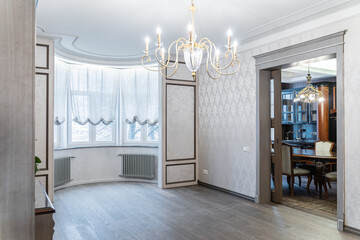 retro interior of large bright living room. Wooden furniture, large chandelier on ceiling, retro chest of drawers. lot of light in room. Illuminated by lamp. Architecture inside home