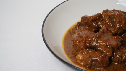 Beef stew is beef stewed with soy sauce and spices, served on a white plate with a white base and background.