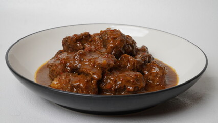 Beef stew is beef stewed with soy sauce and spices, served on a white plate with a white base and background.
