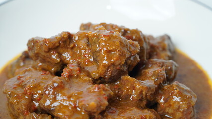 Beef stew is beef stewed with soy sauce and spices, served on a white plate with a white base and background.