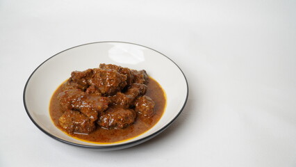 Beef stew is beef stewed with soy sauce and spices, served on a white plate with a white base and background.