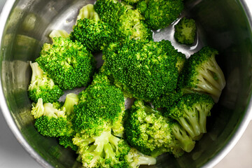 Cooked steamed green broccoli in a stainless steel pot