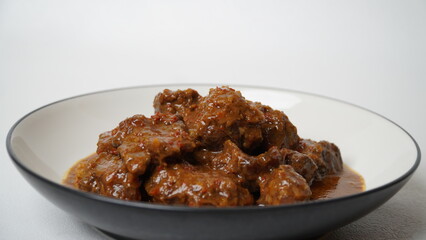 Beef stew is beef stewed with soy sauce and spices, served on a white plate with a white base and background.