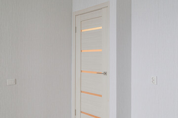modern interior scene features a pale wooden door with horizontal accents, set against textured white walls, with electrical fixtures
