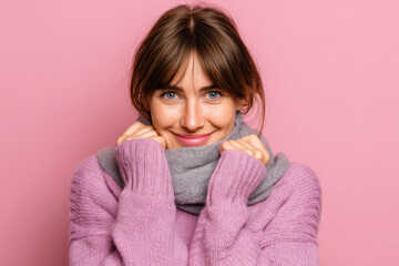 woman with soft scarf wrapped around her embracing herself in cozy light pink background