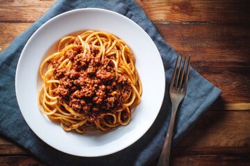 Plate of spaghetti with meat sauce, on a wooden table