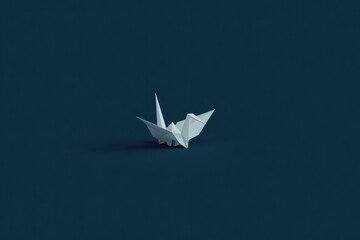 Delicate origami crane placed against deep blue backdrop, symbol
