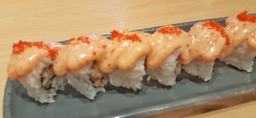 Chicken katsu dynamite roll served on wood table. Food photography presentation
