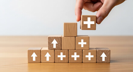 Wooden cubes with plus and upward arrow symbols stacked, hand placing top block, showcasing growth, progress, and positive additions