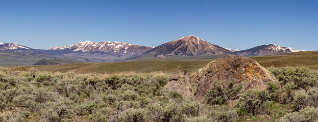 A large volcanic boulder rests in the sagebrush in Ohio Creek Valley outside of Gunnison, Colorado, rising behind the Anthracite Range, Carbon Peak, and Mount Axtell.