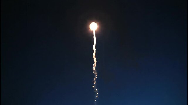 A single firework rocket ascends into the dark night sky, leaving a trail of sparks and smoke.