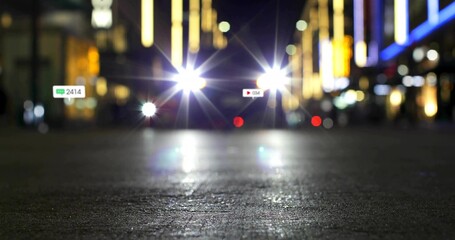 Shining vehicle headlights moving along dark street at night, with floating chat icon and play icon