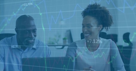 Two colleagues in business attire reviewing financial data on laptop at office desk, chart overlay