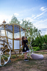 teenage girl standing, light long hair, fabulous white carriage, straightening dress, bracelets on her arm, full length, museum exhibit, outdoors, walk