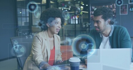 Two business professionals collaborating at office discussing HUD overlays, with laptop and coffee