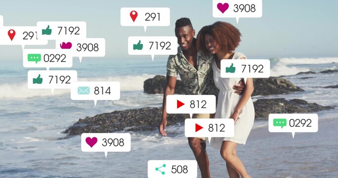 Walking romantic couple in casual summer clothes on sandy shore, with floating social media icons - Powered by Adobe