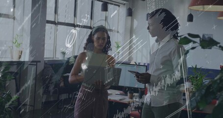 Coworkers reviewing graphs while analyzing data trends in open-plan office, with smartphone tablet