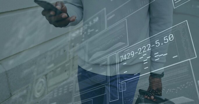 Businessman holding smartphone and briefcase by paneled wall, with digital panels and readouts