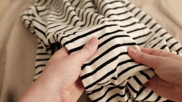Closeup video of hands touching soft wool or polyester knitwear or jersey pullover with a hole in it. Appreciating pleasant texture of high quality clothes, but it is damaged. Manufacturing defect.