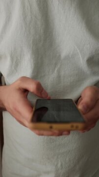Closeup video of an adult man doom scrolling a smartphone. Addictive behavior. Modern world problem. Vertical video.