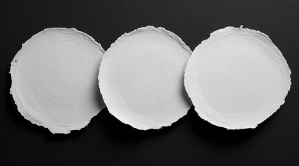 Three circular, torn pieces of white paper on a black background