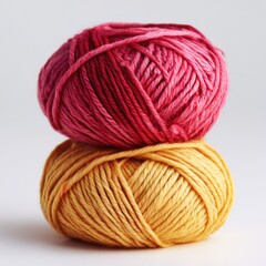 Two skeins of yarn, stacked vertically.  One is a vibrant, ombre pink, the other a warm, golden yellow.  Simple, soft focus