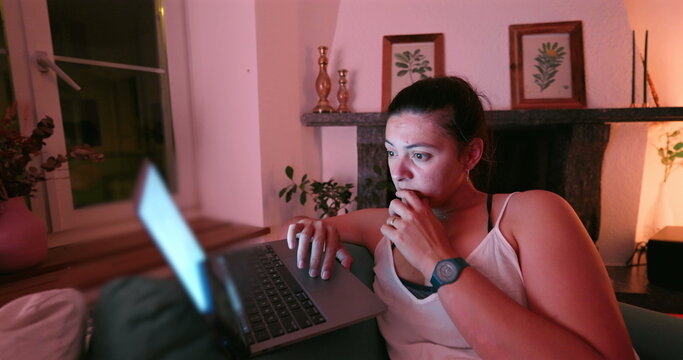 Woman deeply focused on her laptop, working late at night. intense look on her face indicates concentration or concern, illuminated by the glow of the screen in a dimly lit room - Powered by Adobe